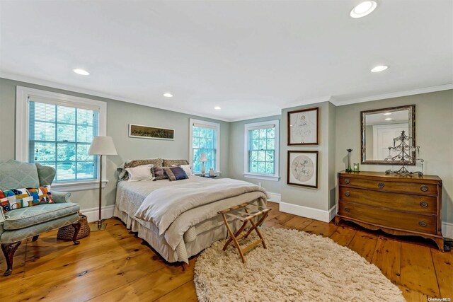 bedroom with multiple windows, wood-type flooring, and ornamental molding