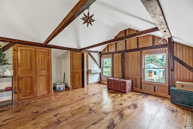 additional living space featuring vaulted ceiling with beams, wooden walls, and light hardwood / wood-style flooring