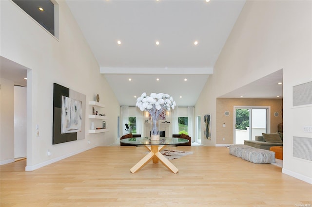 dining room featuring beam ceiling, light hardwood / wood-style flooring, and high vaulted ceiling