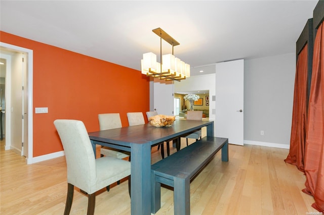 dining area with light hardwood / wood-style flooring and an inviting chandelier