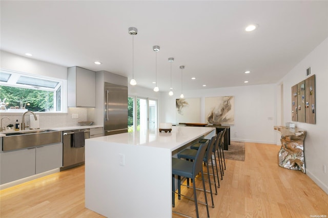 kitchen with a center island, stainless steel appliances, hanging light fixtures, and light hardwood / wood-style floors