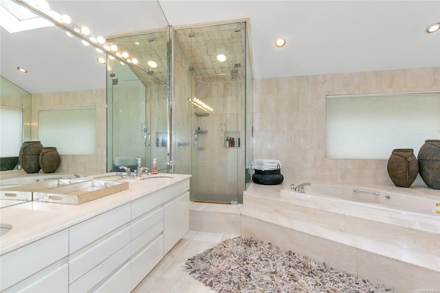 bathroom featuring vanity, tile patterned floors, vaulted ceiling with skylight, separate shower and tub, and tile walls