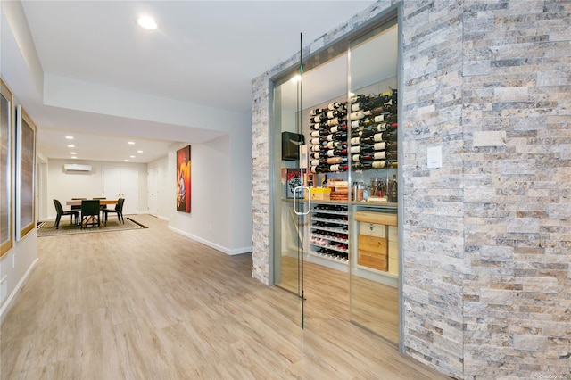 wine room with a wall mounted AC and hardwood / wood-style flooring