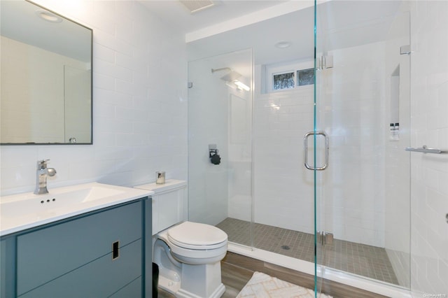 bathroom featuring a shower with door, toilet, wood-type flooring, and tile walls