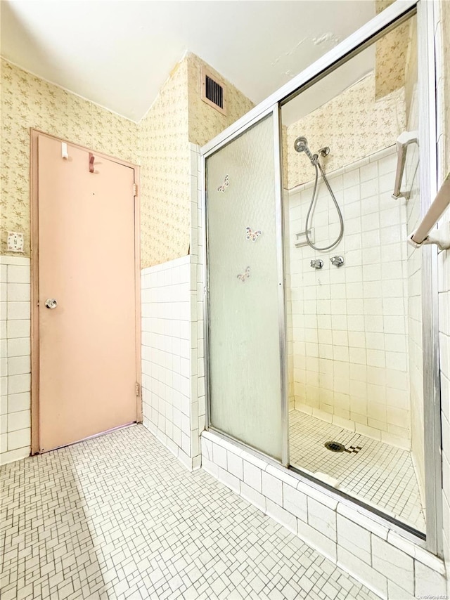 bathroom featuring a shower with shower door and tile walls