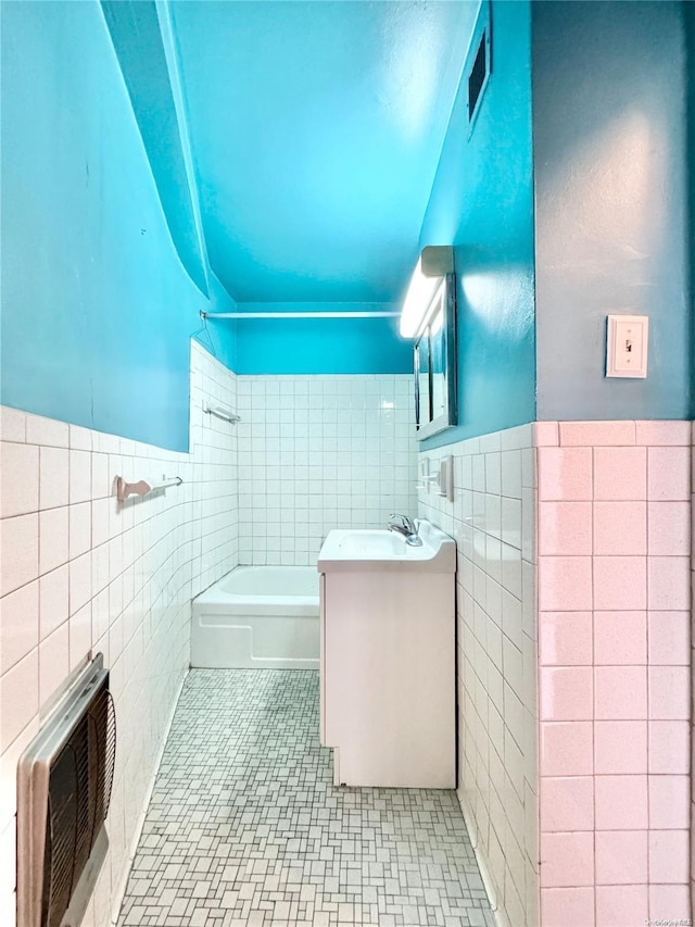 bathroom featuring vanity, heating unit, a tub to relax in, and tile walls