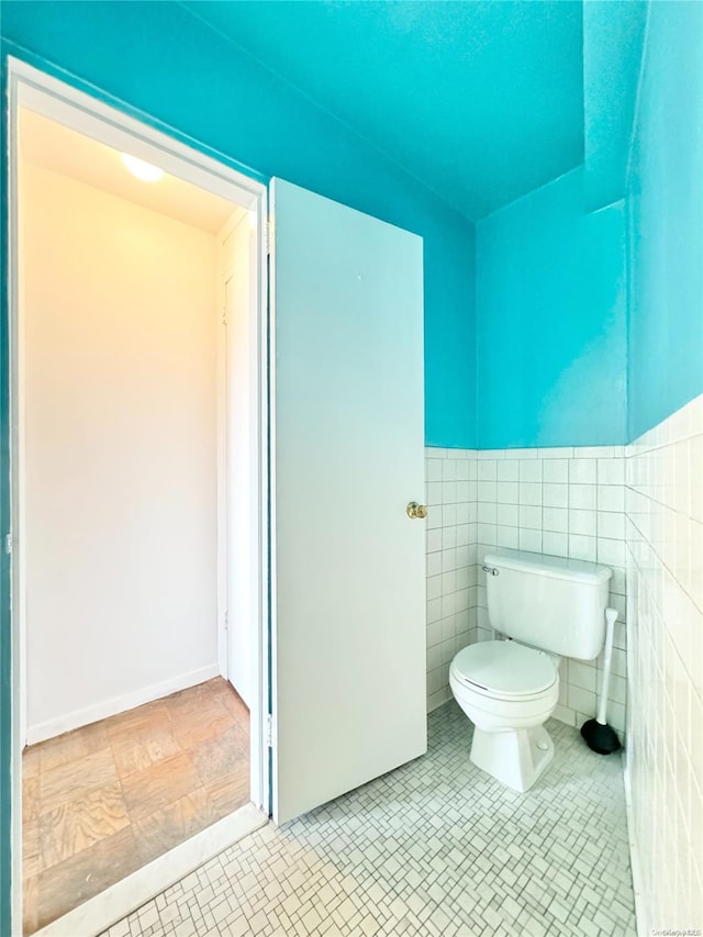 bathroom featuring tile patterned floors, toilet, and tile walls