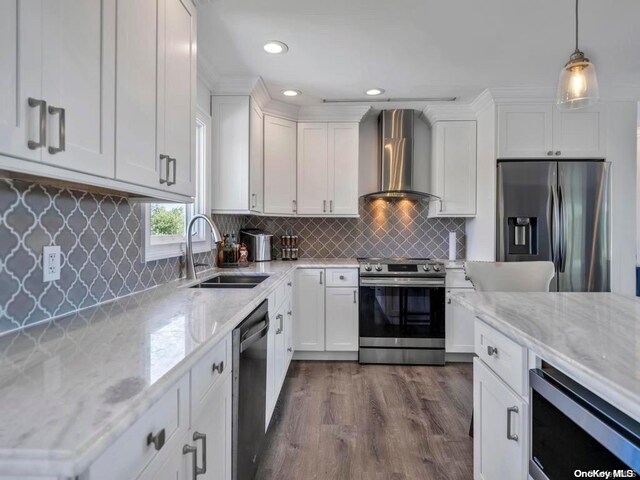 kitchen with appliances with stainless steel finishes, white cabinetry, wall chimney exhaust hood, and sink