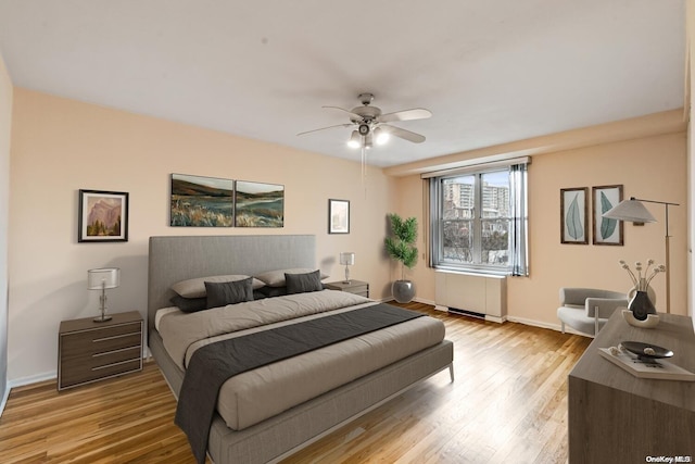 bedroom with radiator, ceiling fan, and light wood-type flooring