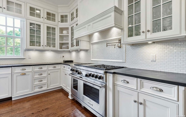 kitchen featuring decorative backsplash, white cabinetry, and range with two ovens