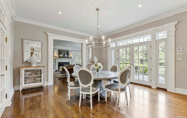 dining room featuring french doors, hardwood / wood-style flooring, crown molding, and a notable chandelier