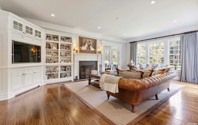 living room with hardwood / wood-style floors, built in features, and ornamental molding