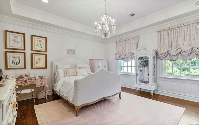 bedroom featuring dark hardwood / wood-style floors, a raised ceiling, crown molding, and an inviting chandelier