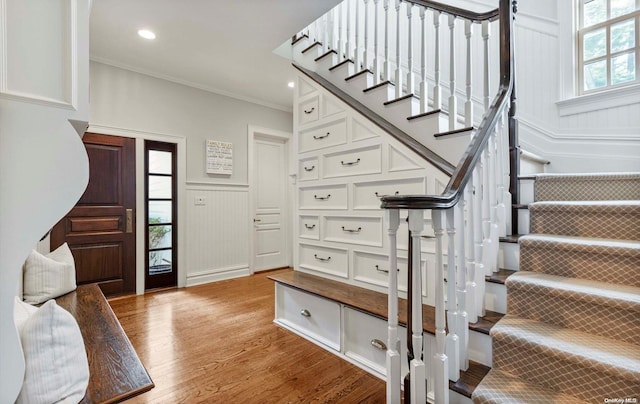 stairs with crown molding and wood-type flooring