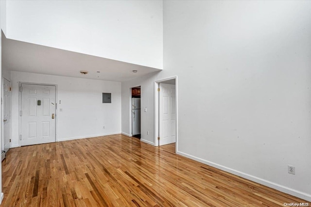 unfurnished living room with light hardwood / wood-style flooring and a high ceiling