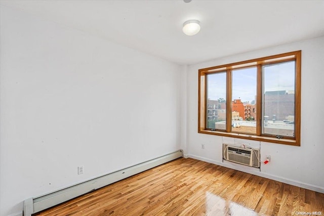 unfurnished room with a wall mounted air conditioner, light hardwood / wood-style floors, and a baseboard heating unit