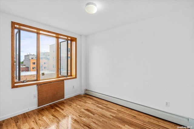 empty room with baseboard heating and light hardwood / wood-style flooring