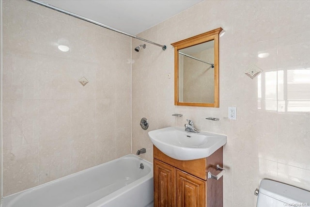 full bathroom featuring vanity, toilet, tile walls, and tiled shower / bath