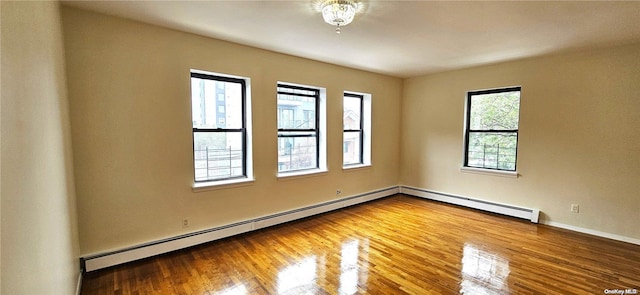 unfurnished room featuring hardwood / wood-style flooring and a baseboard heating unit