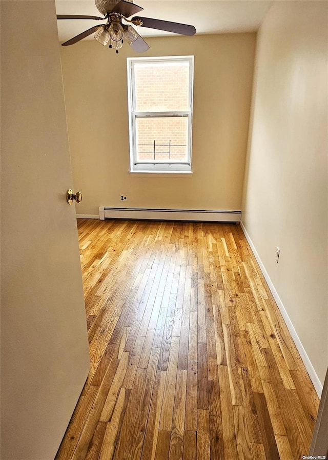 spare room featuring ceiling fan, a baseboard heating unit, and light hardwood / wood-style flooring