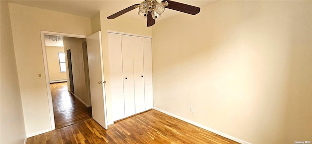 unfurnished bedroom with hardwood / wood-style floors, a baseboard radiator, a closet, and ceiling fan