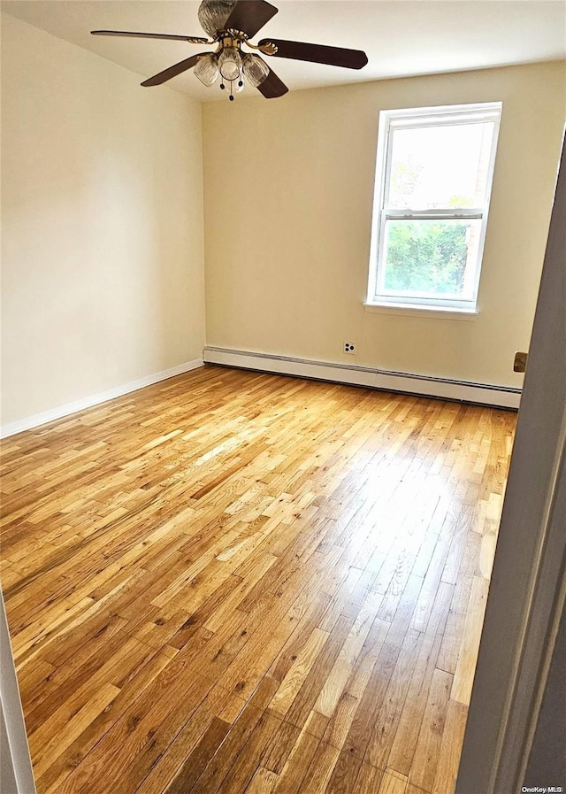 empty room featuring ceiling fan, light hardwood / wood-style floors, and a baseboard heating unit