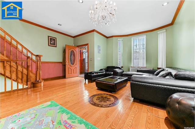 living room featuring wood-type flooring, crown molding, and a chandelier