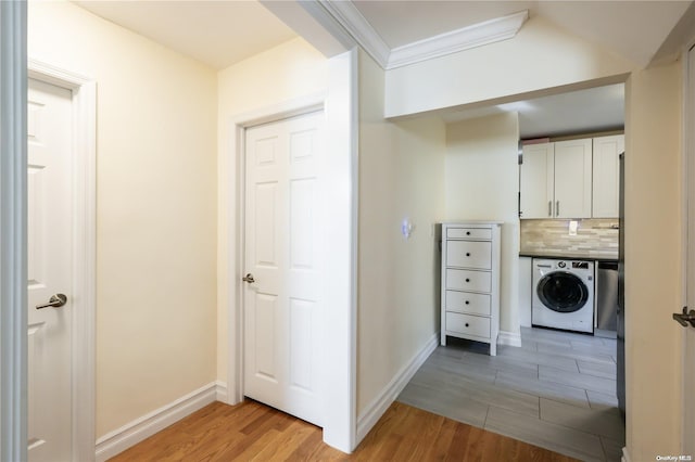 clothes washing area featuring washer / clothes dryer, ornamental molding, and light wood-type flooring