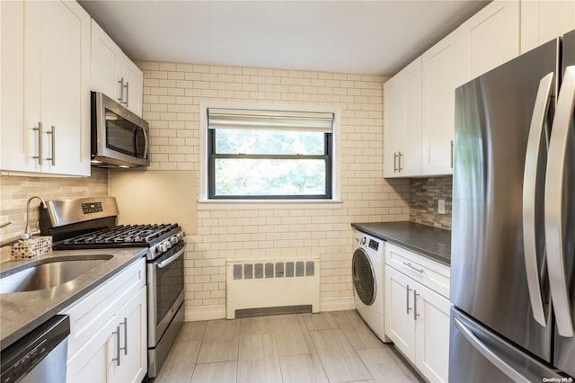 kitchen with washer / clothes dryer, white cabinetry, radiator heating unit, and stainless steel appliances