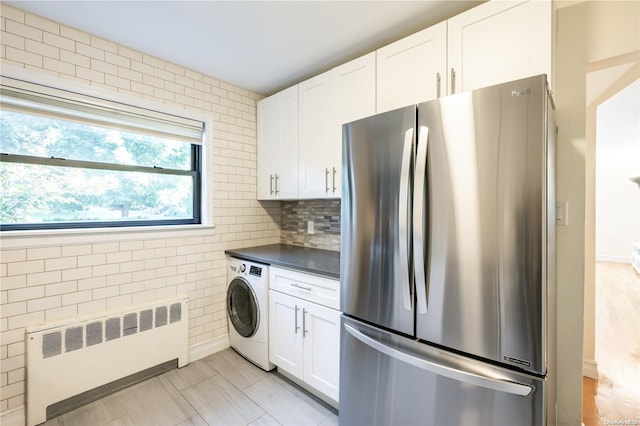 kitchen featuring stainless steel fridge, white cabinetry, radiator, and washer / dryer