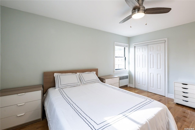 bedroom featuring ceiling fan, light wood-type flooring, radiator, and a closet