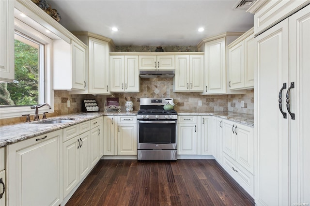 kitchen featuring stainless steel range oven, light stone countertops, sink, and dark wood-type flooring