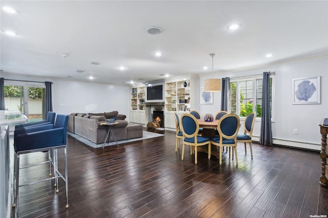 dining space with dark hardwood / wood-style floors, crown molding, baseboard heating, and built in shelves