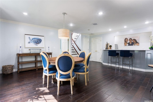 dining room featuring bar area, dark hardwood / wood-style floors, and ornamental molding