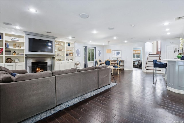 living room with dark hardwood / wood-style floors, crown molding, and a healthy amount of sunlight