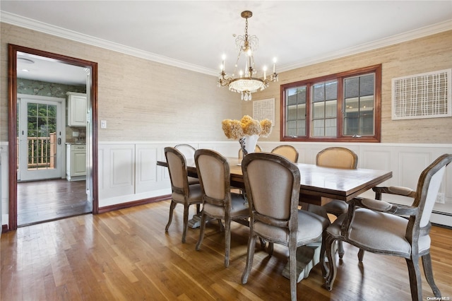 dining area featuring hardwood / wood-style floors, ornamental molding, and an inviting chandelier