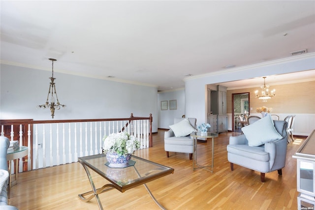 living room featuring light hardwood / wood-style floors, a notable chandelier, and ornamental molding