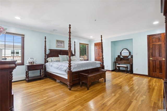 bedroom featuring light wood-type flooring, ornamental molding, and multiple windows