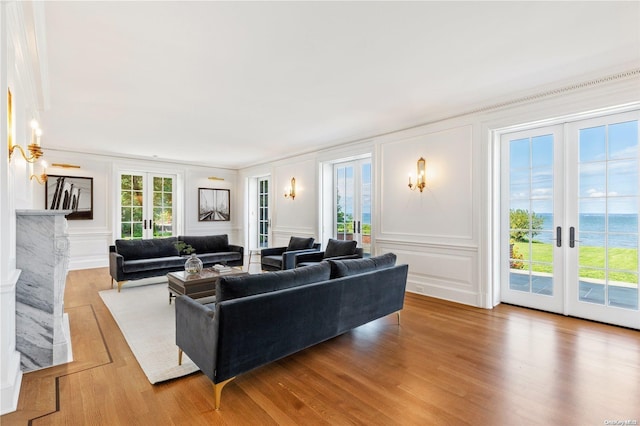 living room with french doors, a water view, crown molding, and hardwood / wood-style floors