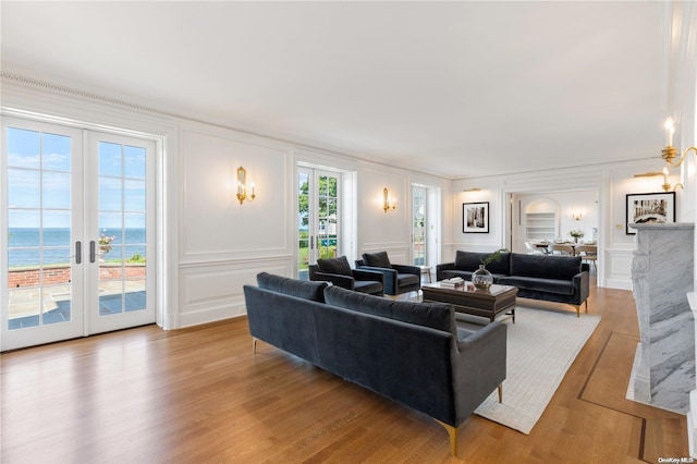 living room with french doors, a water view, and light wood-type flooring