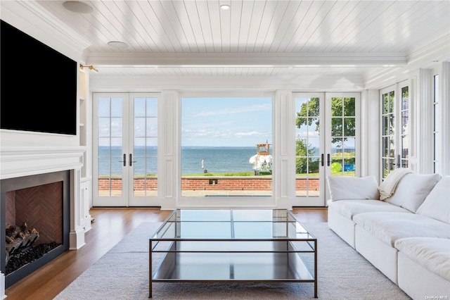 sunroom / solarium with french doors, a water view, and a healthy amount of sunlight