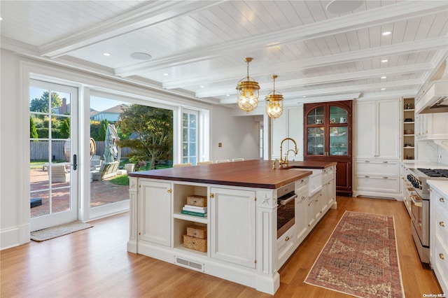 kitchen featuring butcher block counters, an island with sink, a healthy amount of sunlight, and appliances with stainless steel finishes