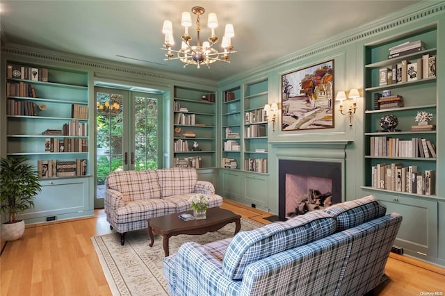 sitting room featuring an inviting chandelier, french doors, light hardwood / wood-style flooring, built in features, and ornamental molding