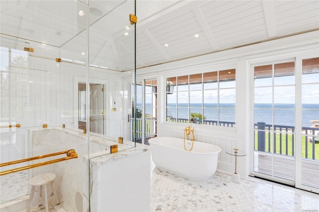 bathroom featuring beamed ceiling, a water view, a tub to relax in, and a wealth of natural light