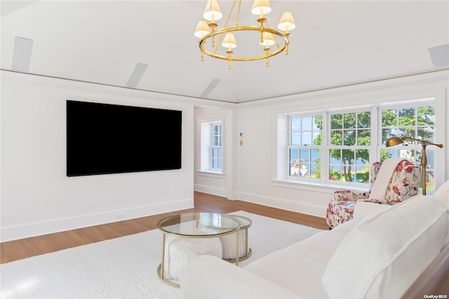 living room featuring a wealth of natural light, a chandelier, lofted ceiling, and hardwood / wood-style flooring