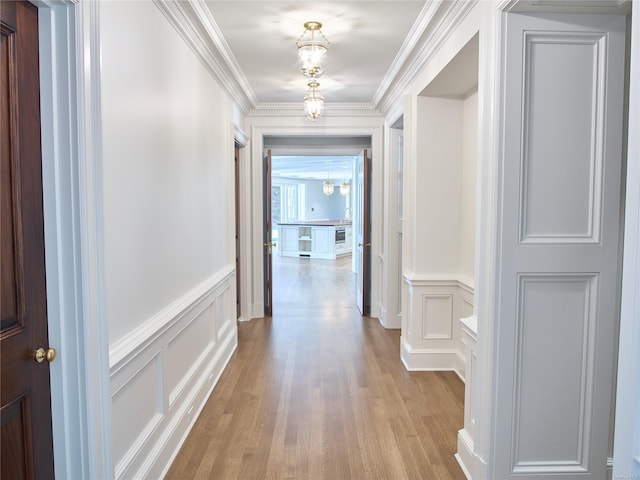 corridor with crown molding and light hardwood / wood-style flooring