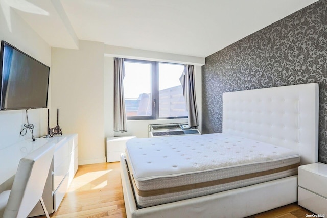 bedroom featuring an AC wall unit and light hardwood / wood-style flooring