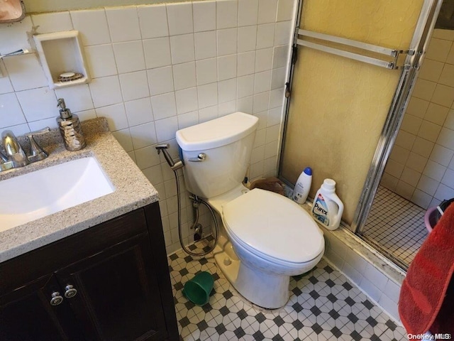 bathroom with vanity, an enclosed shower, tile walls, and toilet