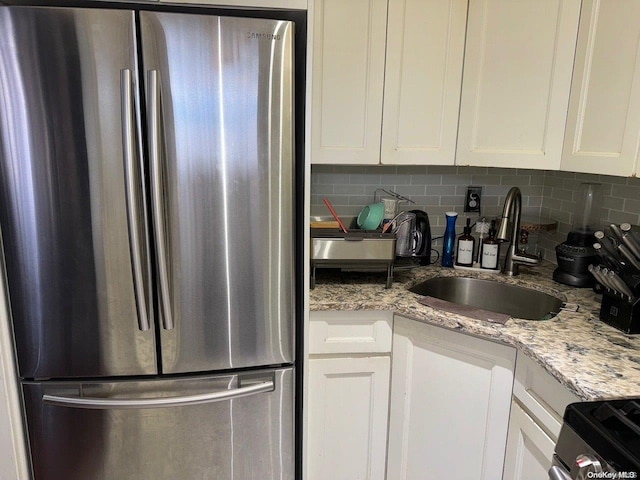 kitchen with white cabinets, sink, backsplash, and stainless steel refrigerator