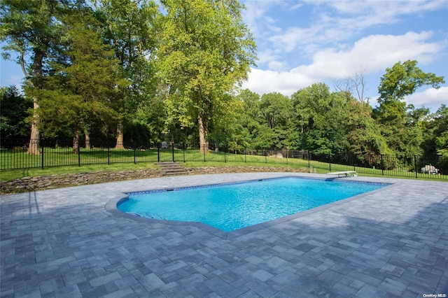 view of swimming pool featuring a patio, a diving board, and a lawn